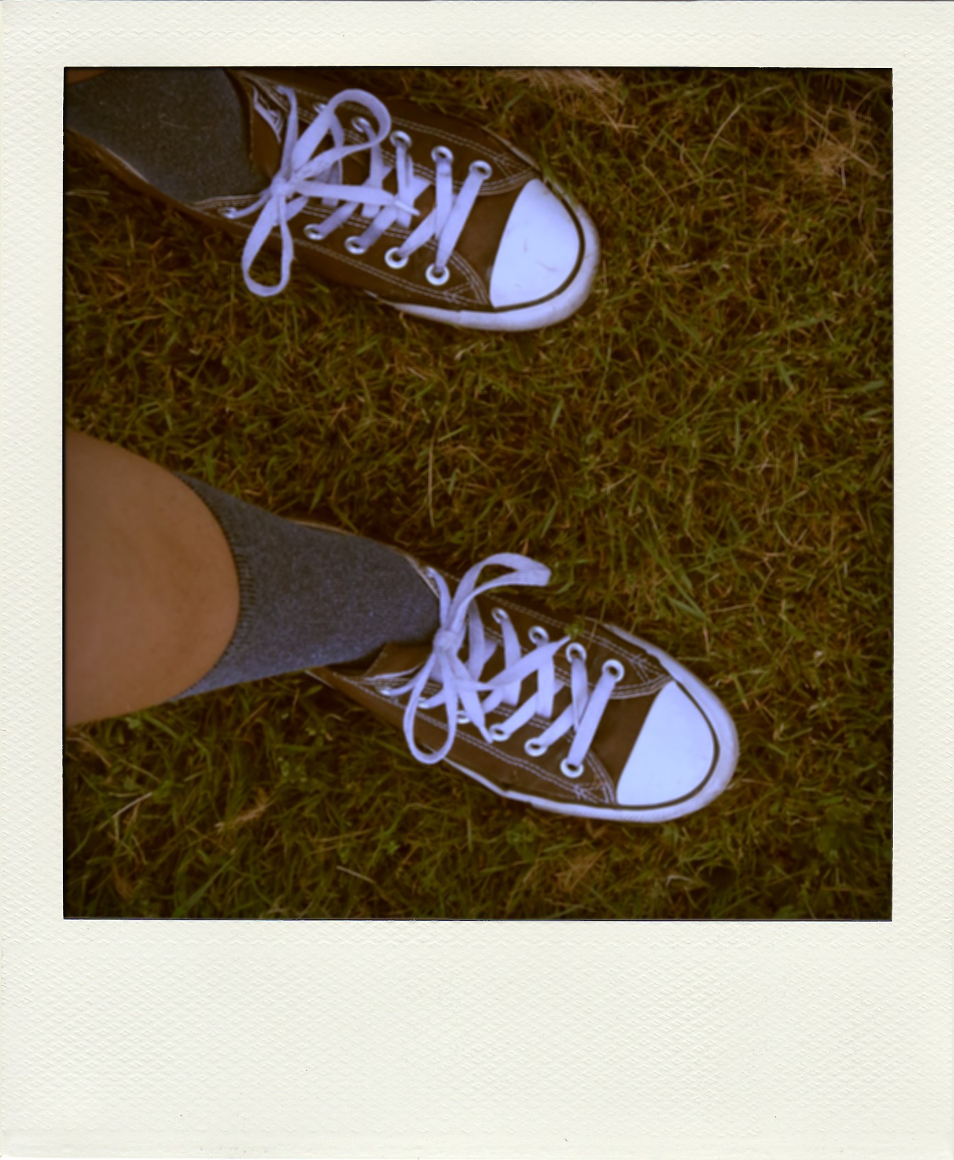My feet on the grass. I'm wearing black Converse sneakers and dark blue socks.