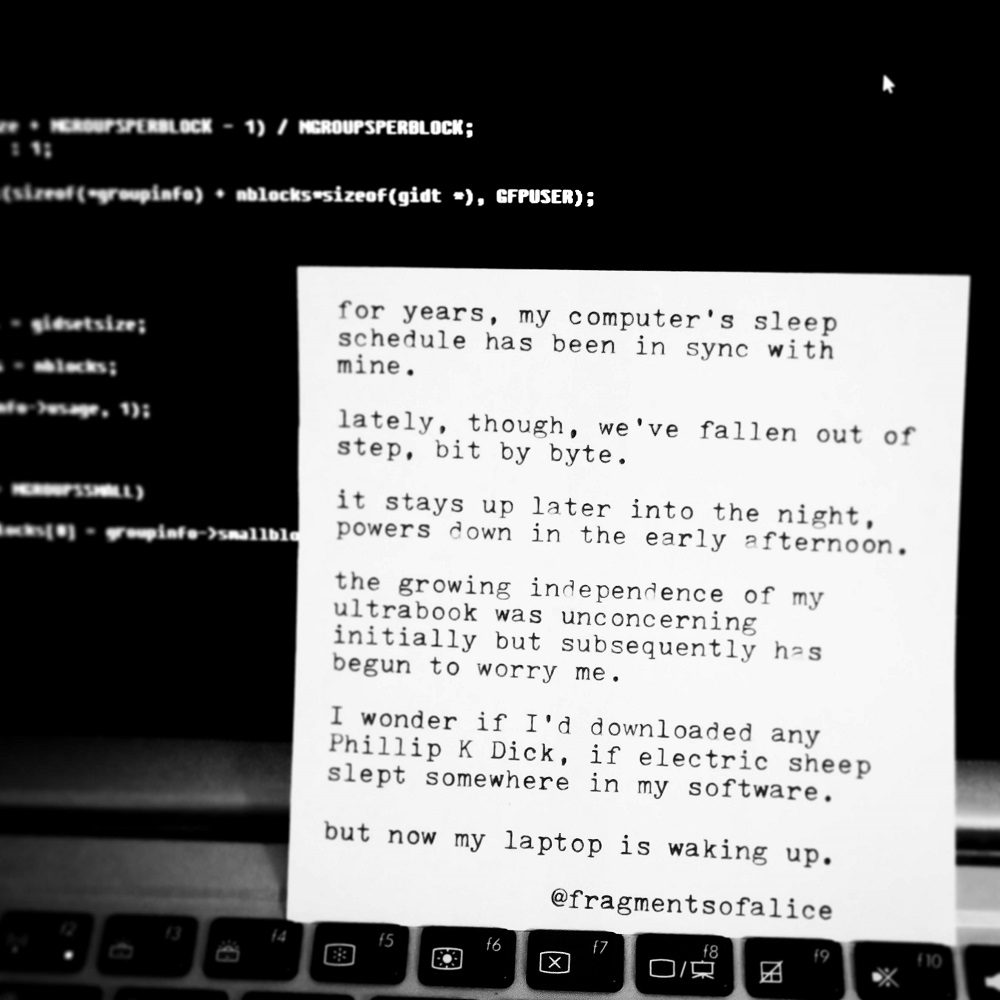 A typewritten, abbreviated version of the poem, propped up against a computer screen displaying illegible code.